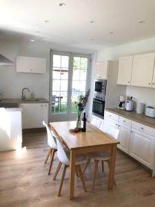 cocina con mesa de madera y armarios blancos en Gîte Niederbronn-les-Bains, en Niederbronn-les-Bains