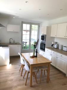a kitchen with a wooden table and white cabinets at Gîte Niederbronn-les-Bains in Niederbronn-les-Bains
