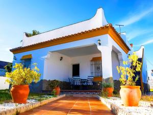 una casa blanca con sillas y flores en su interior en Chalet Piscina Privada Zona Vallada con Barbacoa, en Conil de la Frontera