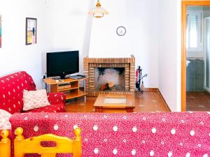 sala de estar con sofá rojo y chimenea en Chalet Piscina Privada Zona Vallada con Barbacoa en Conil de la Frontera