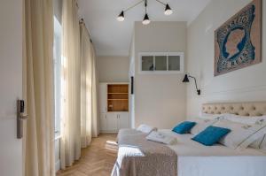 a white bedroom with a bed with blue pillows at Casa dos Correios in Vila Real