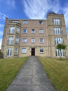 a large brick building with a sidewalk in front of it at Duloch Bridge View in Dunfermline