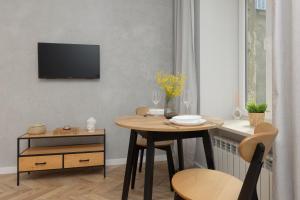 a dining room with a table and a tv on a wall at Twilight Apartment for 3 Guests Warsaw Wola by Renters in Warsaw