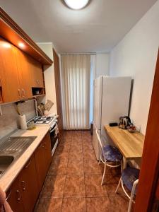 a kitchen with a refrigerator and a table with chairs at Meszlényi Apartman II in Pécs