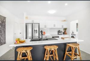 eine Küche mit weißen Schränken und einer Theke mit Stühlen in der Unterkunft Tranquil paradise - whole home - with views! King and Queen beds in Woree