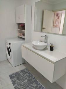 a bathroom with a sink and a washing machine at Simply delightful unit close to CBD and Beach in Perth