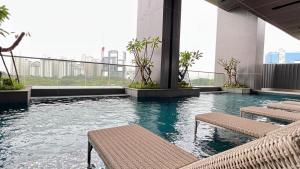 ein Pool mit Bänken auf einem Gebäude mit einer Stadt in der Unterkunft Condo with nearest to JIExpo 55” SMART TV (Netflix & Disney) and Wi-fi 50mb in Jakarta