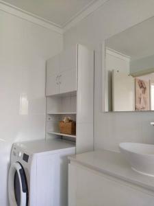 a white bathroom with a washing machine and a sink at Simply delightful unit close to CBD and Beach in Perth