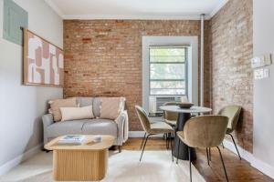 uma sala de estar com um sofá e uma parede de tijolos em East Village 2br w in-unit wd nr nightlife NYC-1236 em Nova York