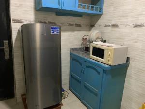 a kitchen with a refrigerator and a microwave on a blue cabinet at Grace apartment in Ofatedo