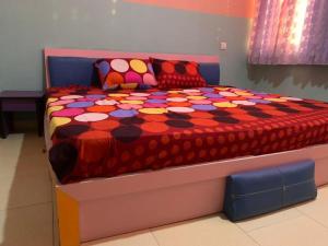 un letto con un piumone colorato e cuscini sopra di Grace apartment a Ofatedo
