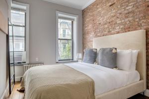 Schlafzimmer mit Ziegelwand und großem Bett in der Unterkunft East Village 2br w in-unit wd nr nightlife NYC-1236 in New York