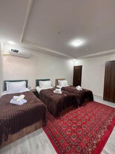 a hotel room with two beds and a red rug at Abuzar in Bukhara