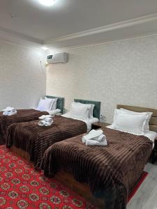 two beds in a hotel room with towels on them at Abuzar in Bukhara