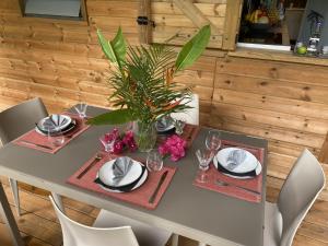 einen Esstisch mit Tellern und Gläsern und eine Pflanze darauf in der Unterkunft Kaz ananas, spa privatif ,plage du Helleux in Sainte-Anne