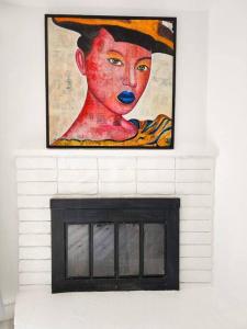 a painting of a woman in a hat on a fireplace at Stylish SD Living (10 min drive to Downtown and 15 min to beach) in Chula Vista