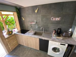 a kitchen with a sink and a washing machine at Kaz ananas, spa privatif ,plage du Helleux in Sainte-Anne