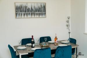 a dining room table with blue chairs and wine bottles at Cosy home with private parking in Bloxwich