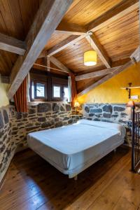 a large bed in a room with a stone wall at Casa de turismo rural Sardom2 in Bembibre