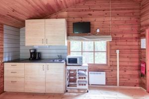a kitchen with wooden cabinets and a microwave and a window at Pinetree Cottages Cozy log cabin in Kalanti