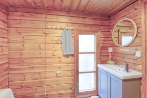 a bathroom with wooden walls and a sink and a mirror at Pinetree Cottages Cozy log cabin in Kalanti