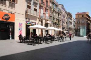 people sitting at tables with umbrellas on a city street at Ca Lanosa in Alicante