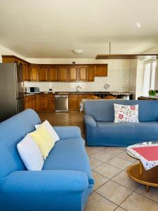 a living room with two blue couches and a kitchen at Appartamento Al Lago in Chiesa