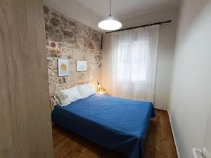 Un dormitorio con una cama azul y una pared de piedra en Εξοχική κατοικία στα Μαστιχοχώρια Χίου, en Chios