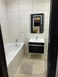 a bathroom with a tub and a sink and a mirror at Lekki holiday shortlet in Lekki