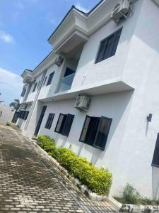 a white building with black windows on a cobblestone street at Lekki holiday shortlet in Lekki