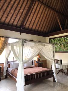 a bedroom with a bed with a canopy at Pande Permai Bungalows in Ubud