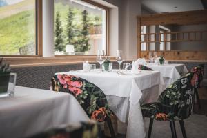 een eetkamer met twee tafels met witte tafelkleden bij Kronplatz-Resort Berghotel Zirm in Valdaora