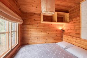 1 dormitorio pequeño con 1 cama en una habitación de madera en Pinetree Cottages Blue Cabin en Pyhäranta