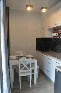 cocina con mesa blanca y sillas blancas en JM Apartament, en Ustronie Morskie