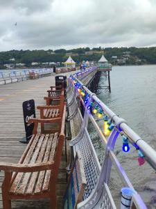 a row of benches on a pier next to the water at Y Garth Guesthouse in Bangor