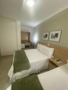 a bedroom with a large white bed and a table at Upper Hotel in Sao Paulo