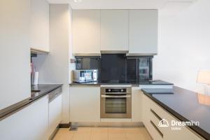 a kitchen with white cabinets and a stove top oven at Dream Inn Dubai Apartments- Premium 1BR Connected to Dubai Marina Mall in Dubai