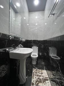 a black and white bathroom with a toilet and a sink at Amirsoy Apple Dacha in Chimgan