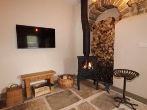 a living room with a wood stove and a tv at The Cow Shed in Holmfirth