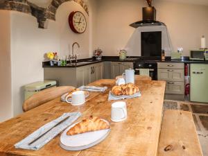 a kitchen with a table with bread and croissants on it at The Cow Shed in Holmfirth