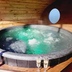 a jacuzzi tub in a wooden room with glasses in it at Vipoilsis Namelis N1 in Čekoniškės