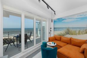 a living room with a couch and a balcony with the ocean at Sea View Studio Apartment Porta Mare by Renters Prestige in Dziwnówek