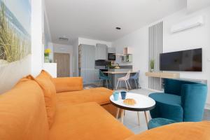 a living room with a orange couch and blue chairs at Sea View Studio Apartment Porta Mare by Renters Prestige in Dziwnówek