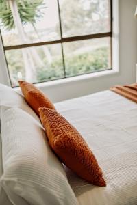 2 almohadas de color naranja en una cama con ventana en Valley View Home - 3 Bdrms, Bay Views, Woodfired Pizza Oven, Firepit, en Port Lincoln
