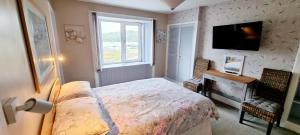 a bedroom with a bed and a desk and a television at The Mariner Hotel in Kippford