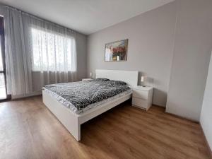 a white bedroom with a bed and a window at Къща Каменар in Pomorie