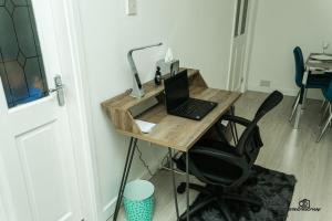 a desk with a laptop and a lamp on it at Cosy home with private parking in Bloxwich