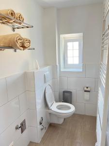 a white bathroom with a toilet and a window at Gasthaus Sonnenblume in Salzburg