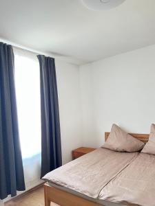 a bedroom with a bed with blue curtains and a window at Gasthaus Sonnenblume in Salzburg