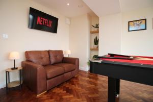 een woonkamer met een bank en een piano bij LUXURY 4 Bedroom 4 Ensuite Home in Penarth (Pool Table Games Room & BBQ Garden) with Sea Views in Cardiff